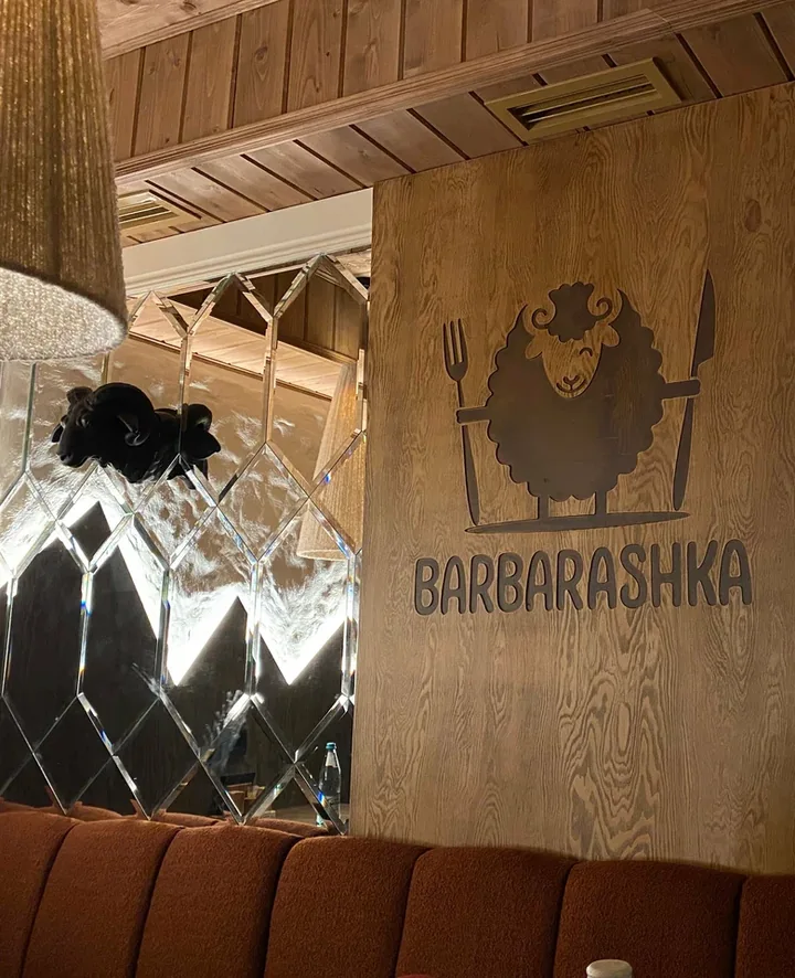 Зал ресторана с зеркальными панелями, деревянной отделкой и диванами терракотового цвета