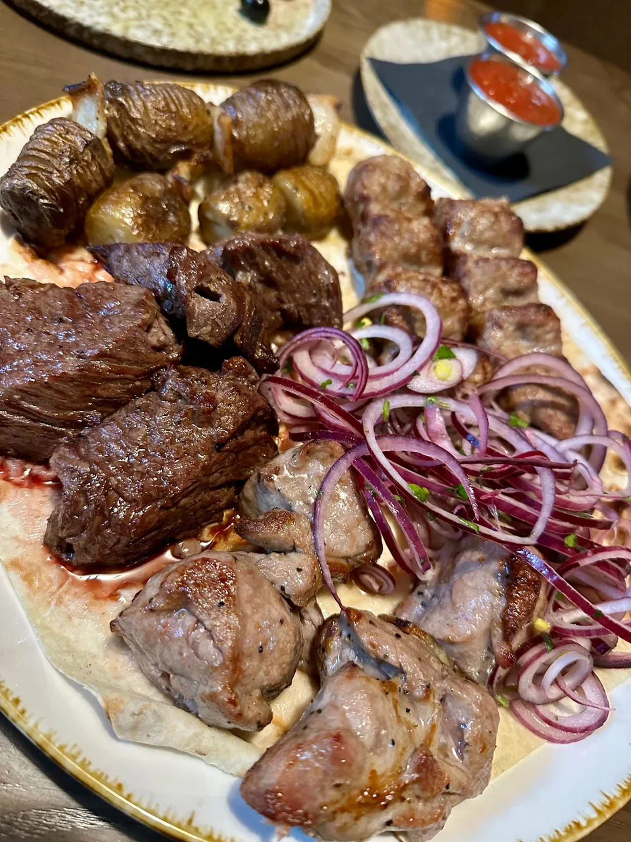 Мясное ассорти с соусами на столе в тёплом освещении
